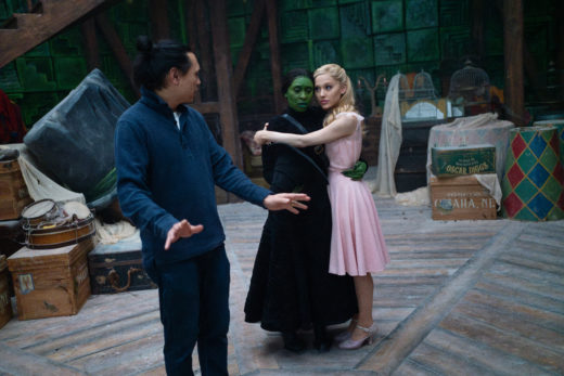 L to R: Director Jon M. Chu with Cynthia Erivo (as Elphaba) and Ariana Grande (as Glinda) on the set of WICKED