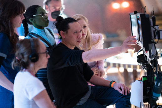 Center L to R: Cynthia Erivo (as Elphaba), Director Jon M. Chu, and Ariana Granda (as Glinda) on the set of WICKED