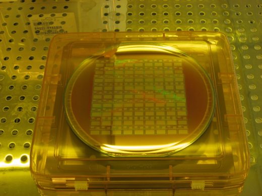 Silicon wafer under the yellow light of a semiconductor manufacturing plant with rows of chips exposed.