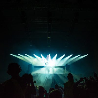 Multiple beams of light focussed on a DJ at a nightclub.