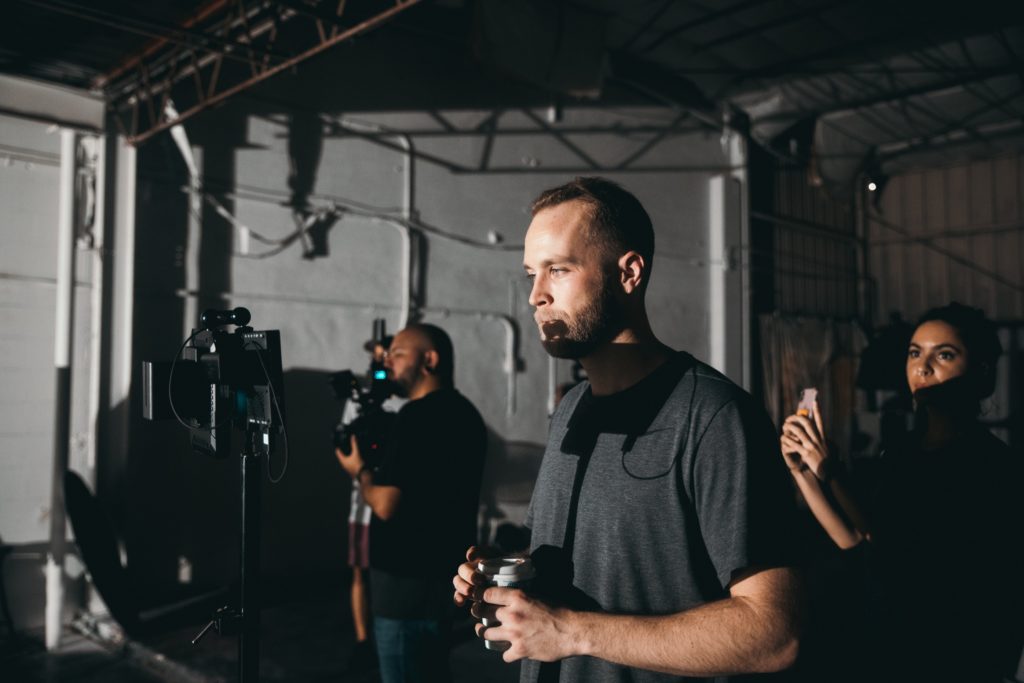 Two men and a woman working as part of a film crew, with one man watching a monitor.