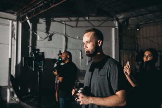 Two men and a woman working as part of a film crew, with one man watching a monitor.