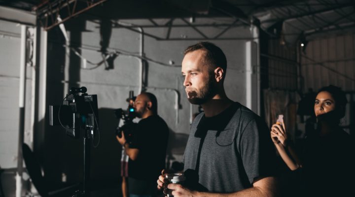 Two men and a woman working as part of a film crew, with one man watching a monitor.