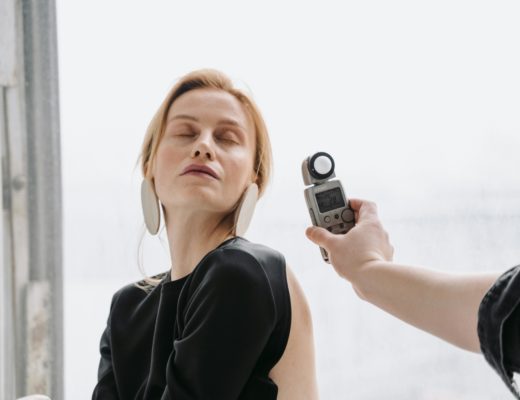 A hand holding a light meter near a woman's face .