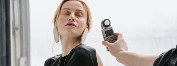 A hand holding a light meter near a woman's face .