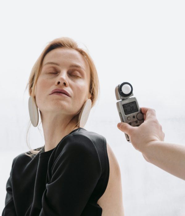 A hand holding a light meter near a woman's face .