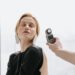 A hand holding a light meter near a woman's face .