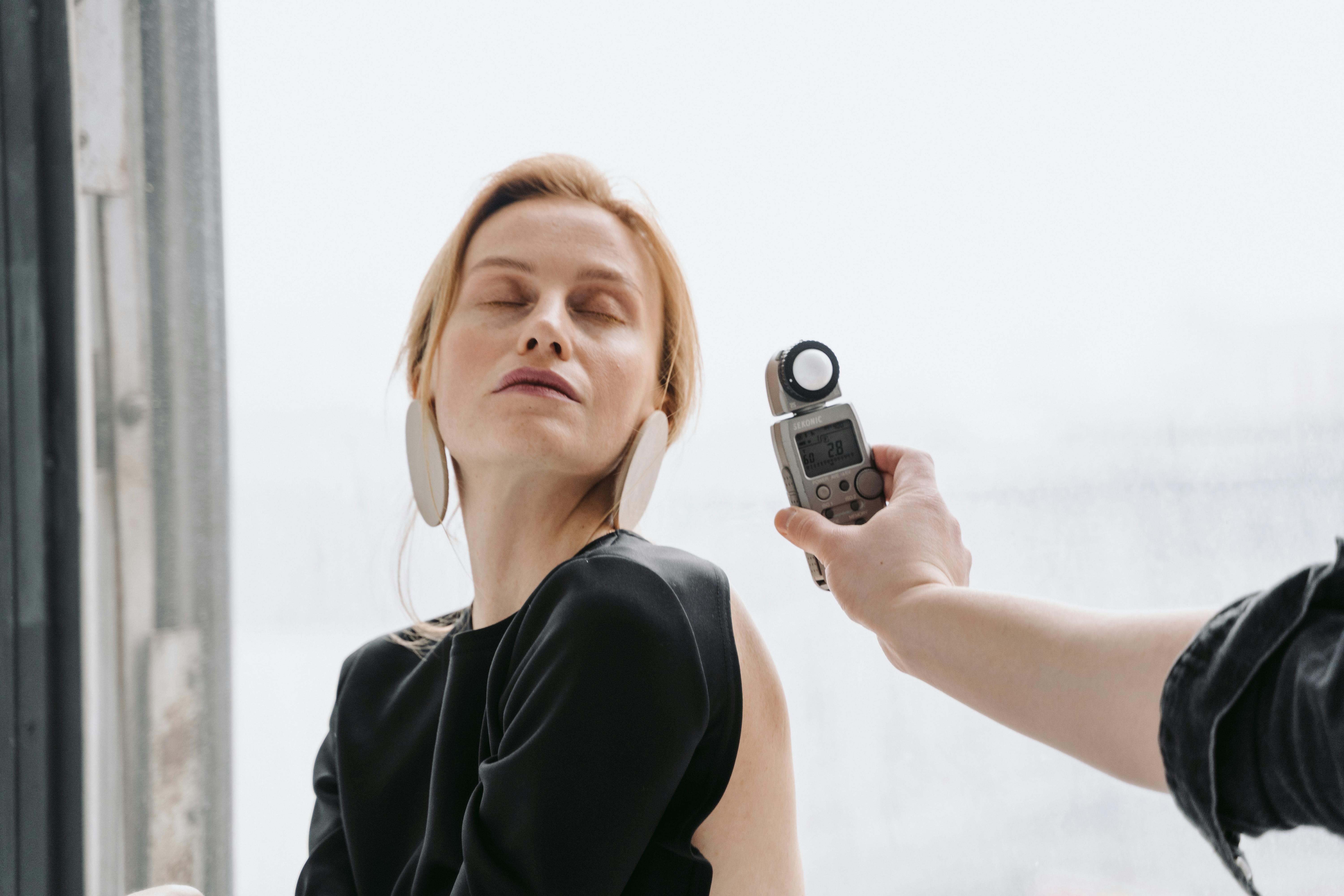 A hand holding a light meter near a woman's face .