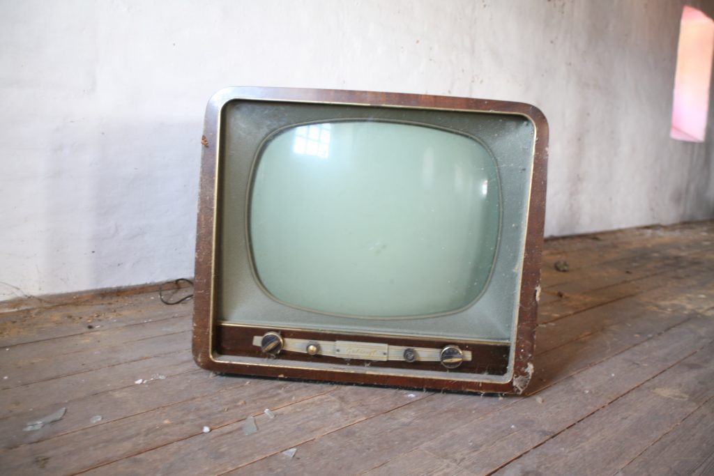 An old-style cathode ray tube TV, covered in spider webs.